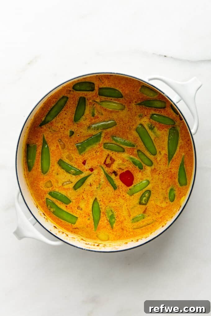 Quick and Creamy Thai Massaman 9 Vibrant vegetables simmering in a creamy, golden Massaman curry sauce in a white pot.