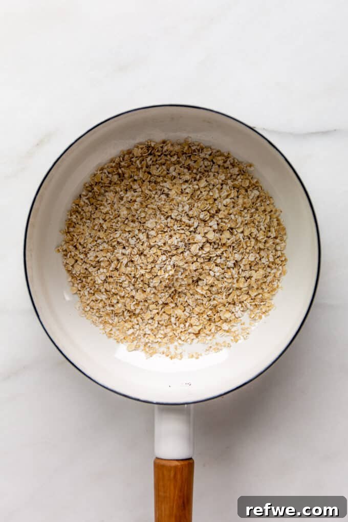 Nutty Oatmeal Delight 4 Dry quick oats being toasted in a white ceramic pot on a stovetop.