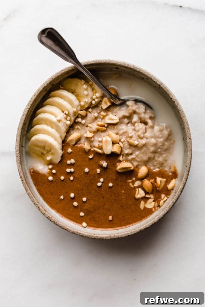 Nutty Oatmeal Delight 6 A close-up of a finished bowl of peanut butter oatmeal, topped generously with sliced bananas, a spoonful of peanut butter, and a sprinkle of peanuts.