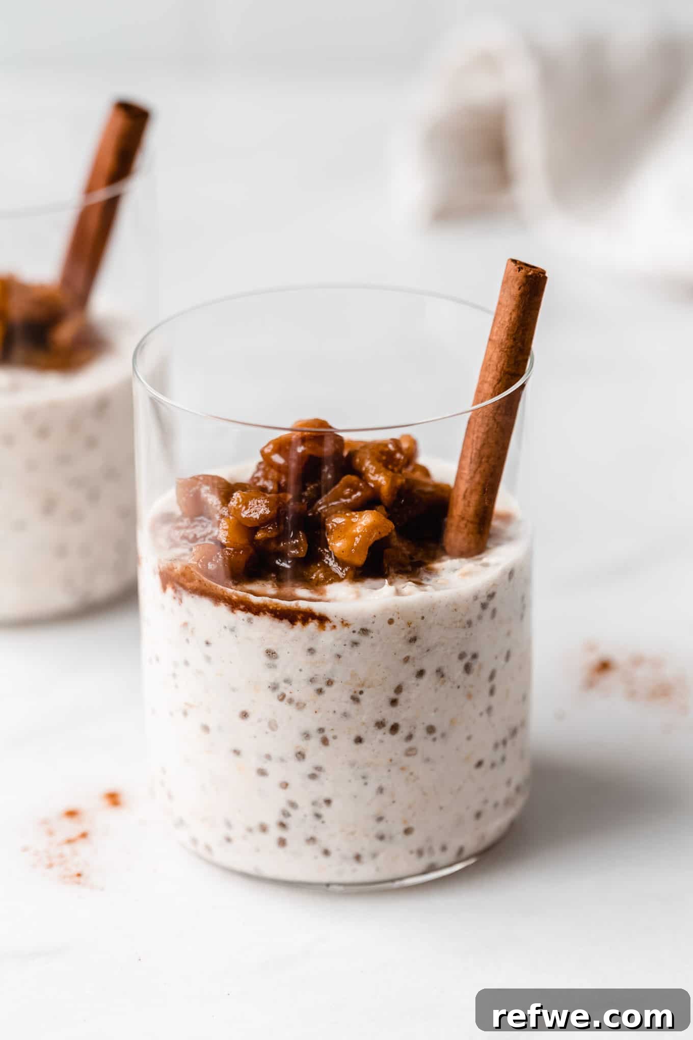 No-Bake Apple Pie Oats 2 A cup of apple overnight oats topped with stewed apples and a cinnamon stick, ready to be enjoyed.