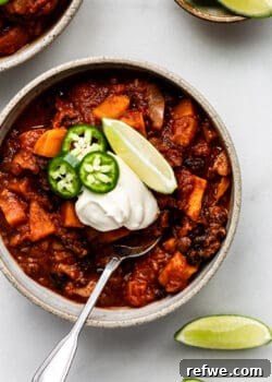 A bowl of sweet potato chili with lime, jalapeño and sour cream