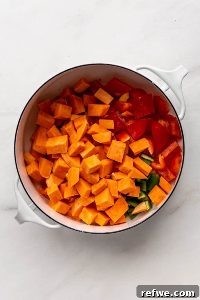 Hearty Sweet Potato Black Bean Chili 6 Cubed sweet potatoes added to the sautéed vegetables in a white pot.