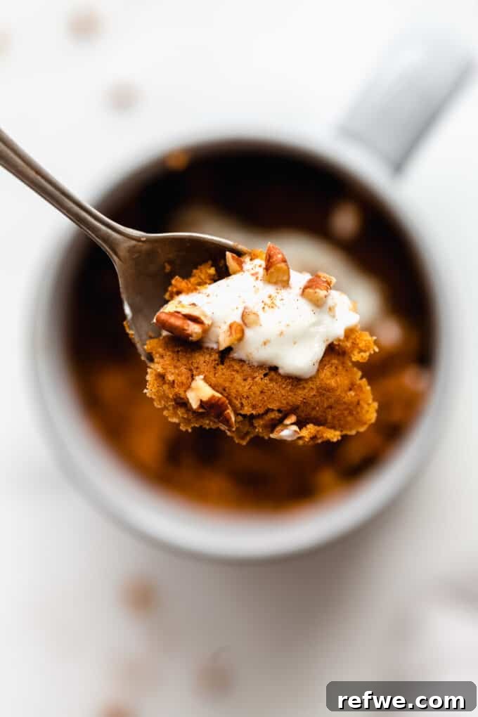 Warm Pumpkin Spice Mug Bliss 7 A close-up of a spoonful of rich pumpkin cake, beautifully topped with a swirl of whipped cream