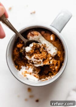 a spoon scooping pumpkin cake out of a mug