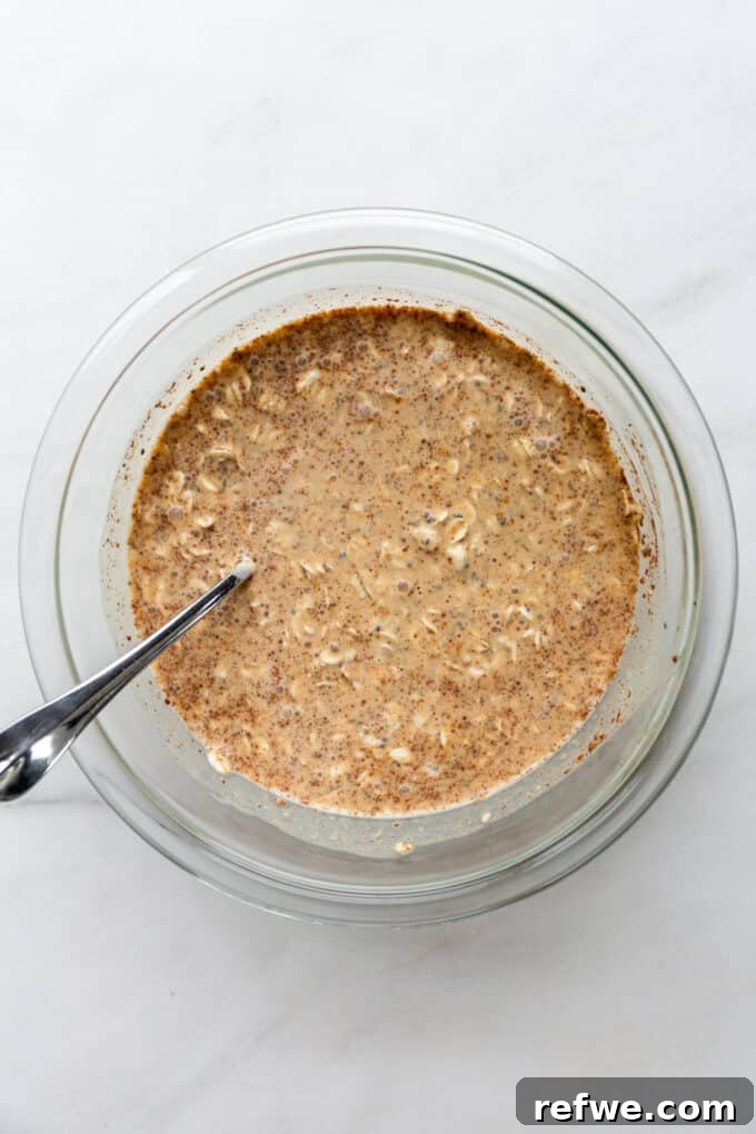 Overnight Autumn Pumpkin Delight 6 Pumpkin overnight oats mixture in a clear mixing bowl, thoroughly combined and ready for chilling.