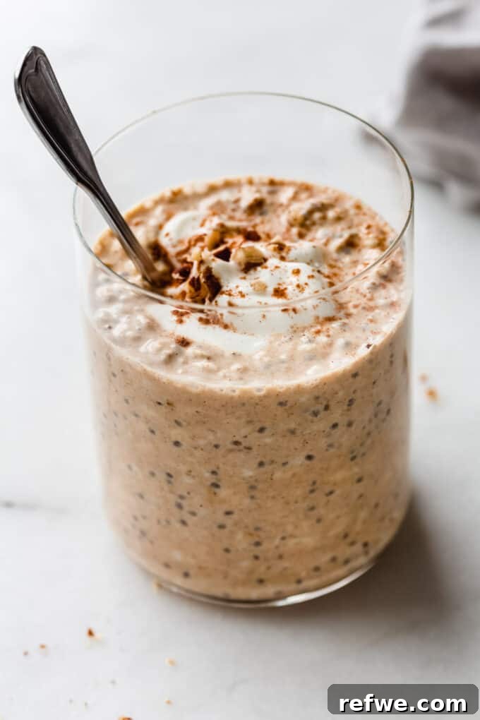 Overnight Autumn Pumpkin Delight 7 A single cup of pumpkin overnight oats with a spoon, topped with a dash of cinnamon, ready to be enjoyed.
