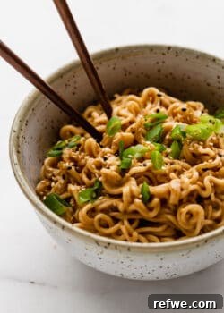 Peanut ramen noodles in a bowl with green onions, ready to serve.