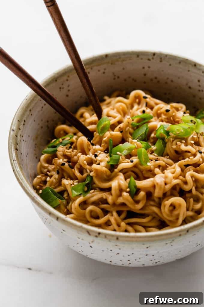 A perfectly plated bowl of peanut ramen noodles, generously topped with fresh green onions, ready for a delicious meal.