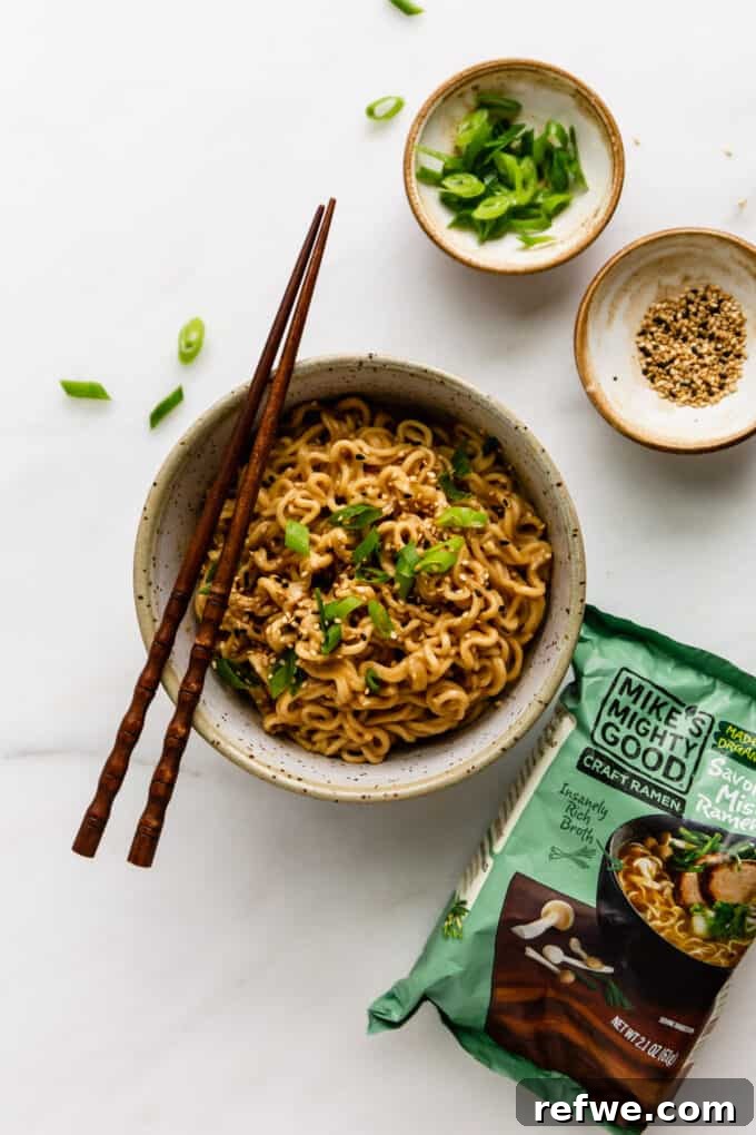 A bowl of Thai Peanut Butter Ramen Noodles accompanied by an unopened pack of Mike's Mighty Good ramen, emphasizing the dish's convenience and ease of preparation.
