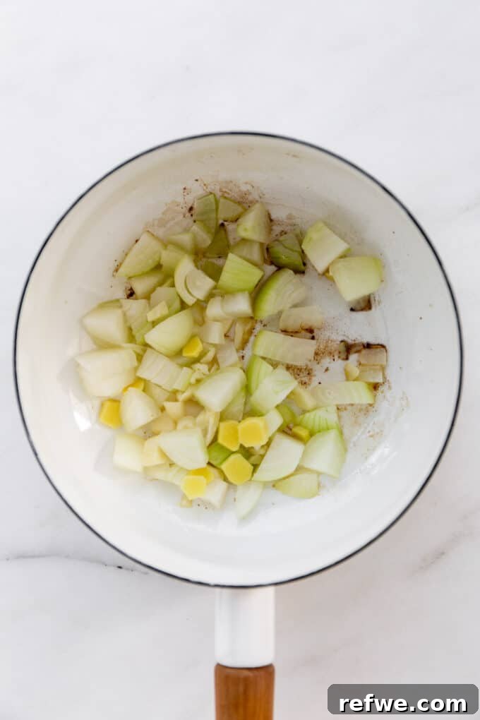 chopped onions, garlic, and ginger sautéing in a white pot