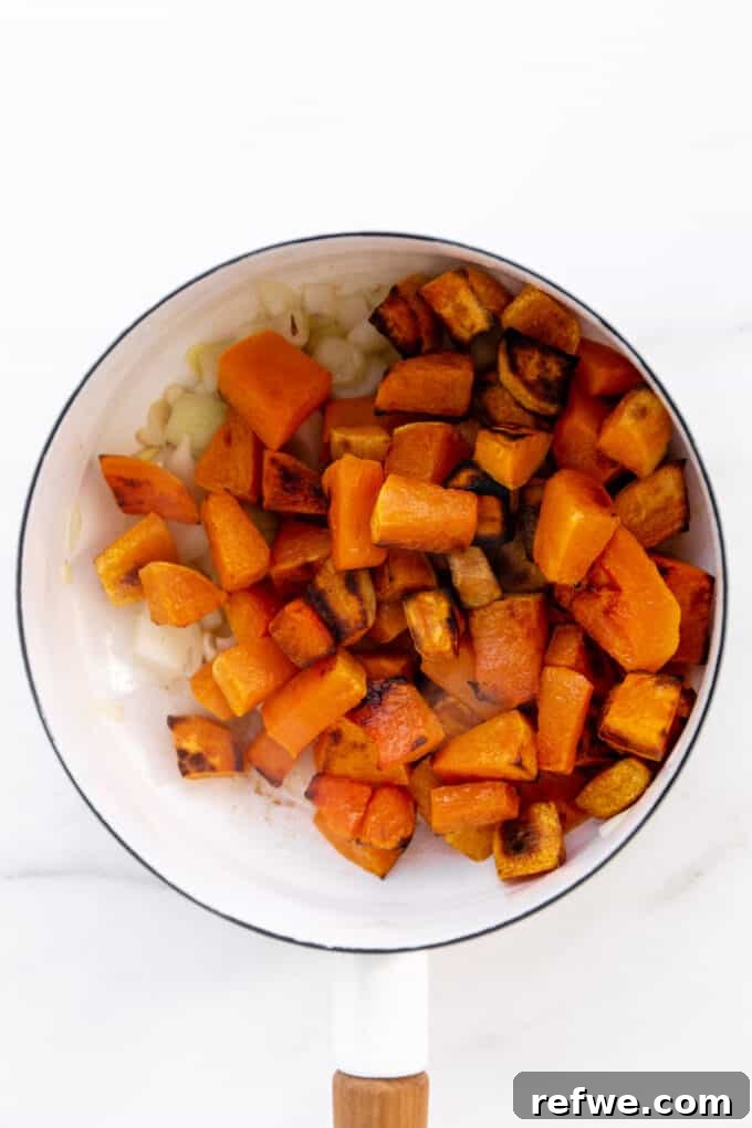 roasted butternut squash and sweet potato combined with sautéed aromatics in a white pot