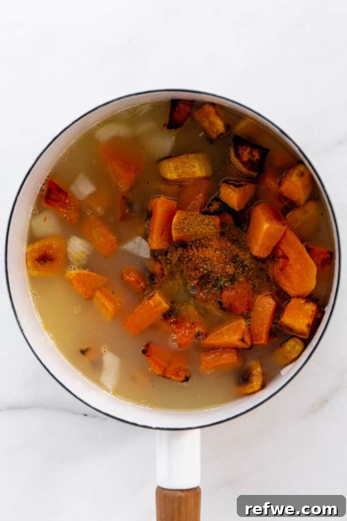butternut squash, sweet potato, and vegetable broth simmering with spices in a white pot