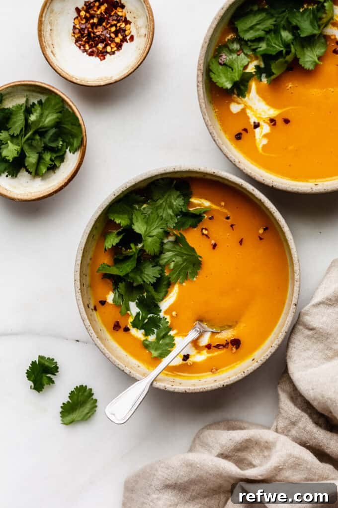 two bowls of butternut squash sweet potato soup elegantly presented with a beige napkin on the side