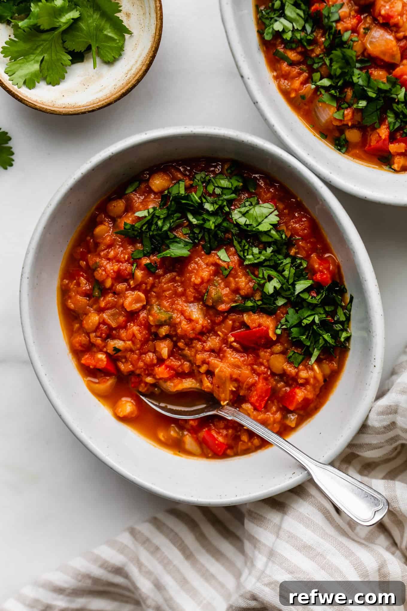 A vibrant bowl of homemade lentil chili, garnished with fresh cilantro, ready to be enjoyed.
