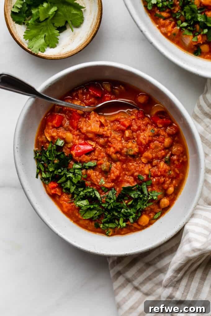 A close-up shot of a bowl of delicious lentil chili with a spoon, showcasing its rich texture and inviting warmth.
