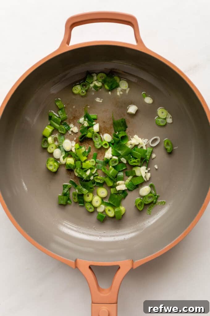 Wholesome Quinoa Stir-Fry 3 Sautéing scallions and garlic in a pink pan, releasing their fragrant aromas.