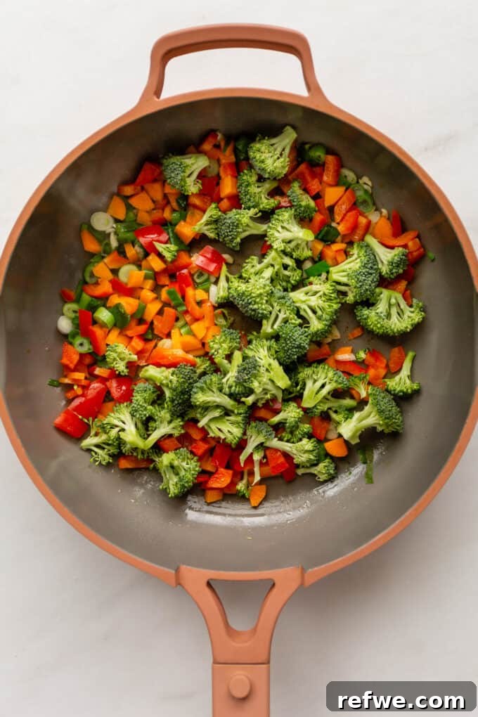 Wholesome Quinoa Stir-Fry 4 A vibrant mix of broccoli, bell peppers, carrots, and scallions cooking in a pan, colorful and tender-crisp.
