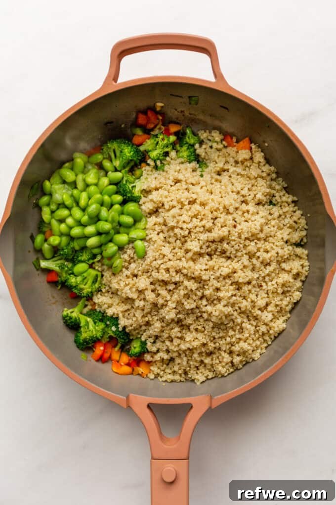 Wholesome Quinoa Stir-Fry 5 Quinoa, edamame beans, and sautéed vegetables mixing together in a pink pan, absorbing the sauce.