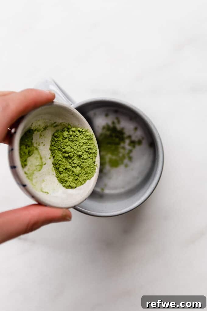 A measurement of matcha powder being carefully poured into a mug.