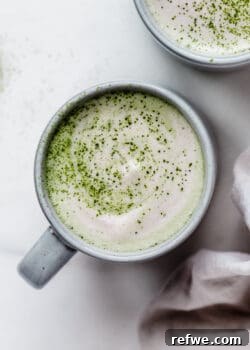 A vibrant matcha latte in a blue ceramic mug, perfectly frothed.