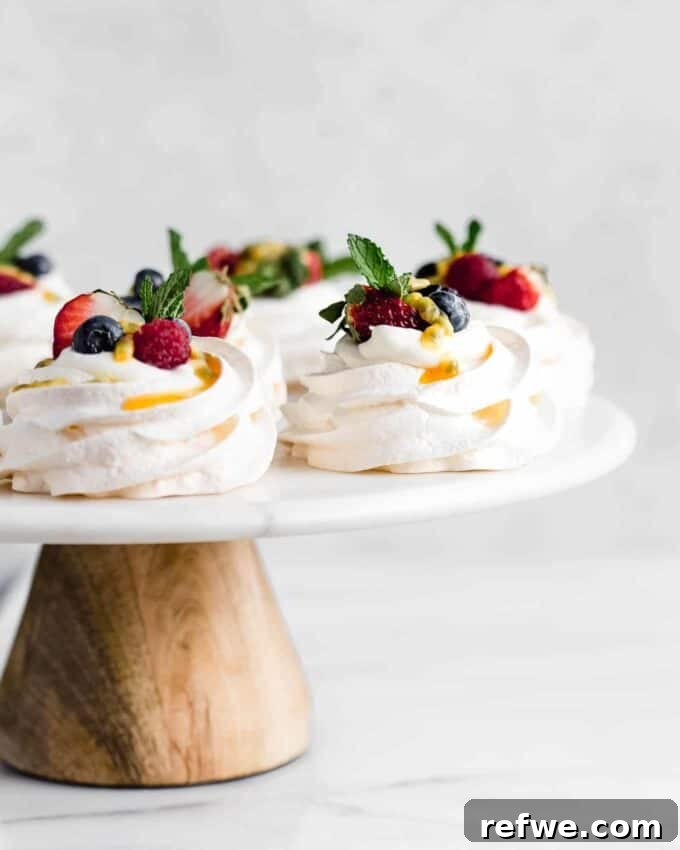 Festive & Fit: 18 Healthier Holiday Treats 5 Elegant Mini Pavlovas topped with fluffy coconut whipped cream and fresh berries, a light, dairy-free, and gluten-free healthy holiday dessert.