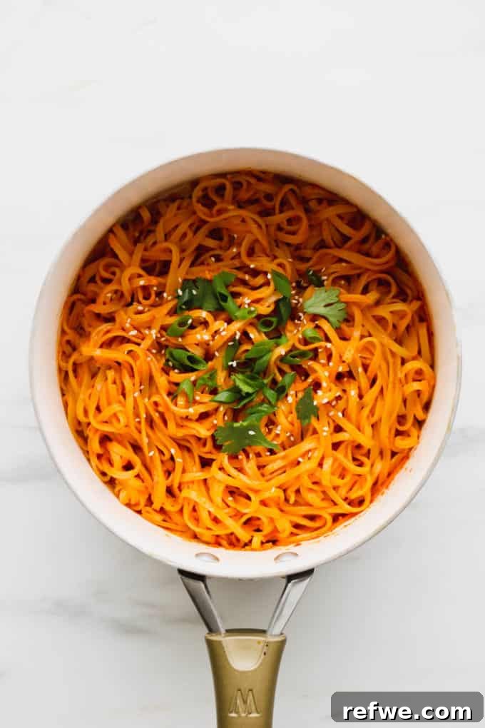 Spicy Thai Red Curry Noodles 11 Thai Red Curry Noodles topped with scallions and cilantro in a white pot, ready to serve