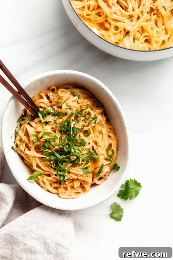 Spicy Thai Red Curry Noodles 12 A bowl of red curry noodles with chopsticks resting on a marble board, ready to eat