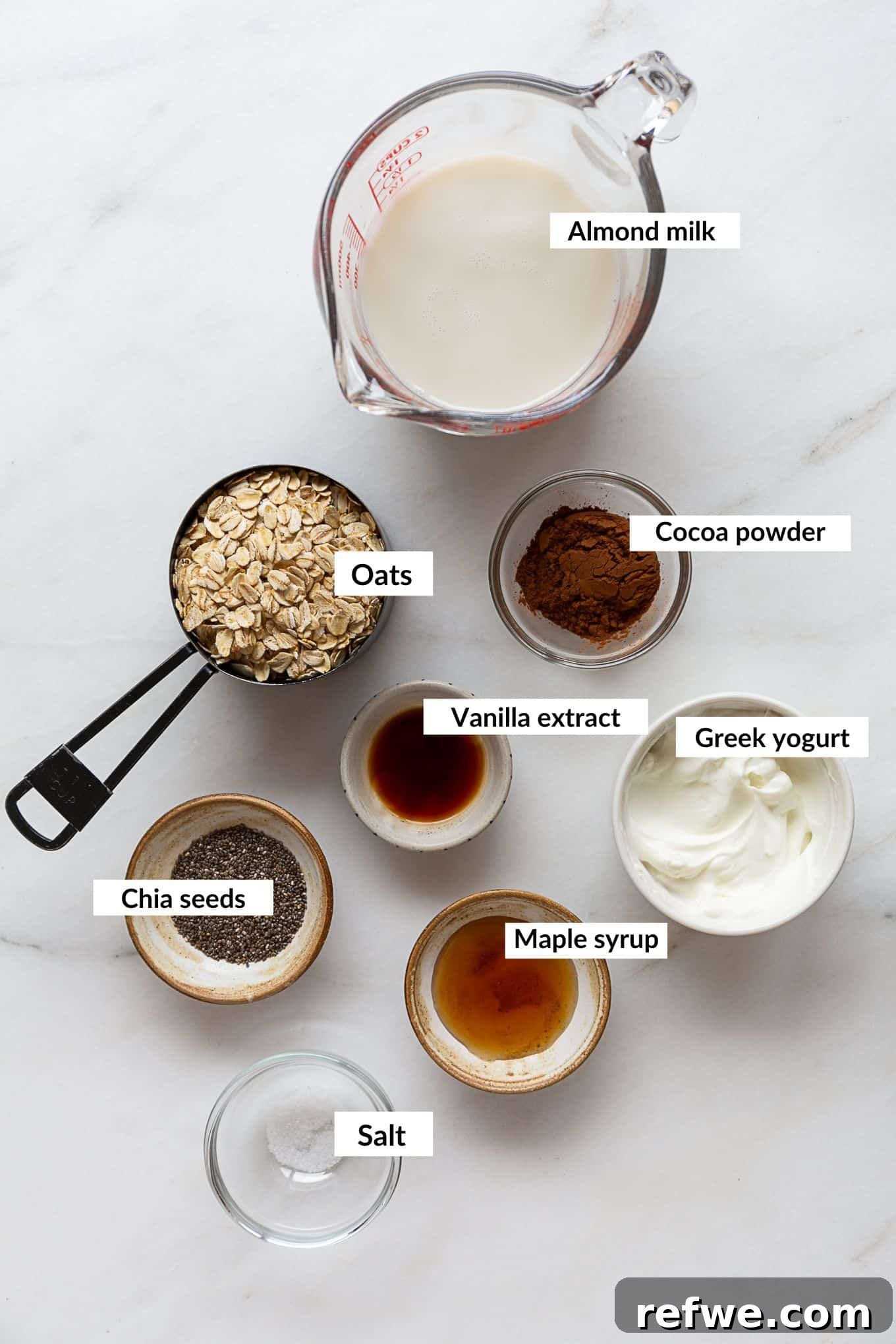Decadent Chocolate Overnight Oats 3 A flat lay photograph showcasing the essential ingredients needed to prepare homemade chocolate overnight oats, including oats, chia seeds, cocoa powder, and liquid.