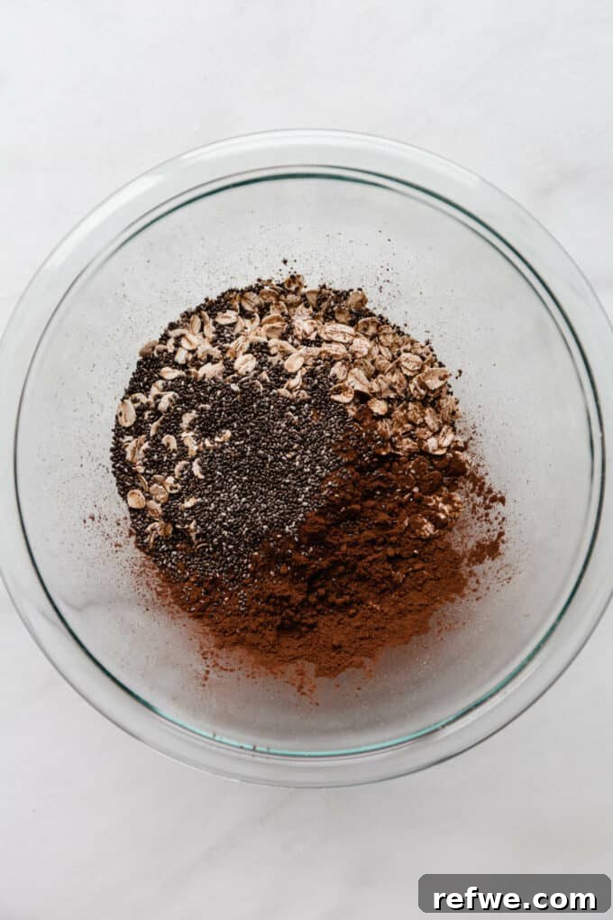 Decadent Chocolate Overnight Oats 4 A bowl containing dry ingredients for chocolate overnight oats: rolled oats, chia seeds, and cocoa powder.