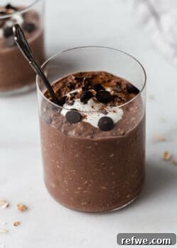 A cup of chocolate overnight oats with a spoon in it, ready to be enjoyed.