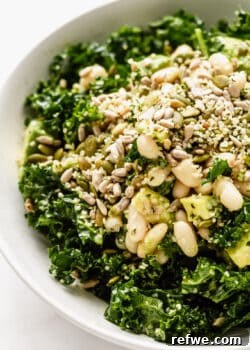 Hearty Kale and White Bean Power Bowl 10 close up of kale salad in a bowl with white beans, avocado and seeds