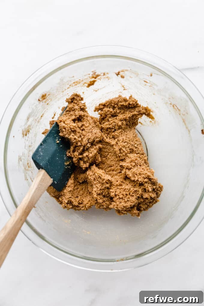 almond flour cookie dough forming in a mixing bowl after dry ingredients are added