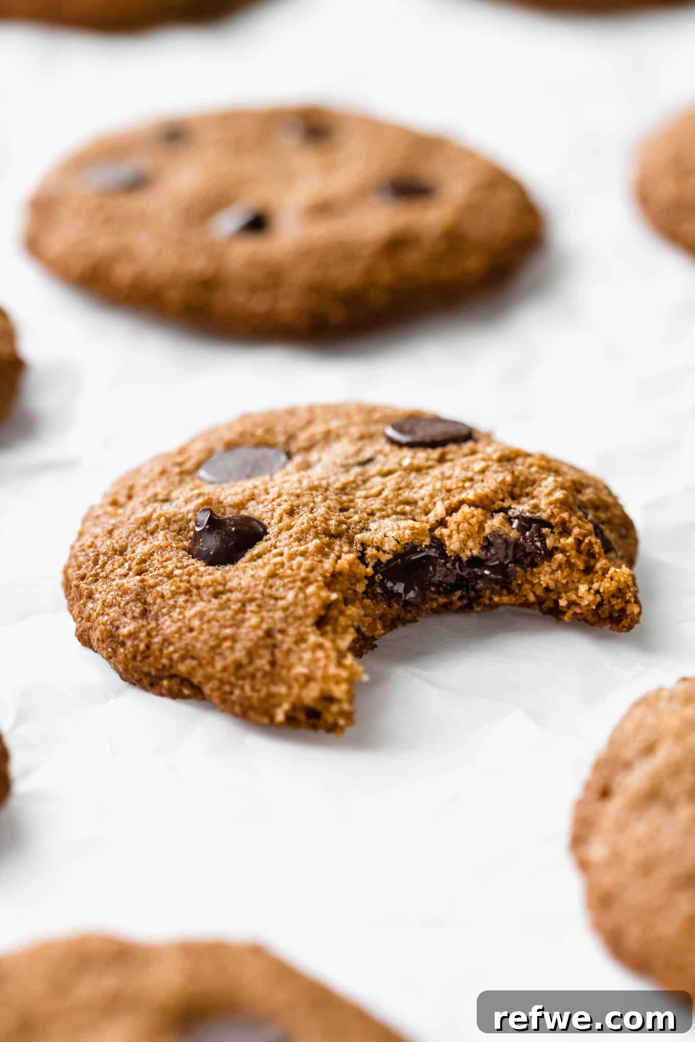 an almond flour chocolate chip cookie with a bite taken from it, showing the soft interior and melted chocolate