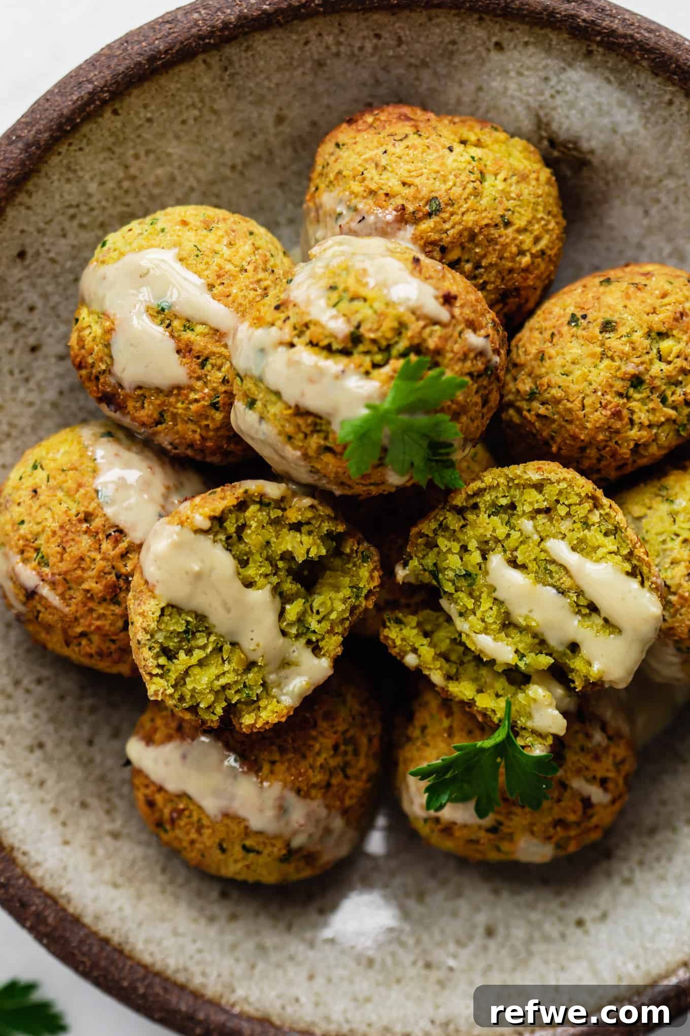 Crispy Air Fryer Falafel 9 falafel balls on a plate topped with tahini and parsley
