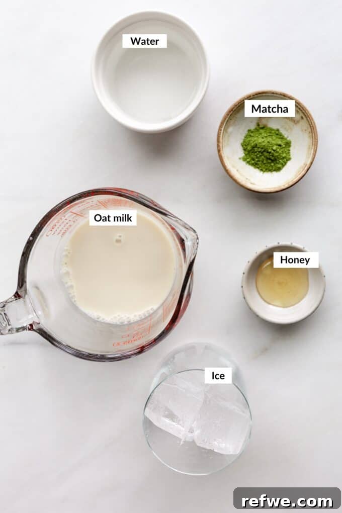 Zen Matcha Chill 3 A flat lay image displaying the key ingredients for an iced matcha latte: matcha powder, a jar of honey, a bottle of vanilla extract, a glass of oat milk, and ice cubes, all arranged artfully on a light background.