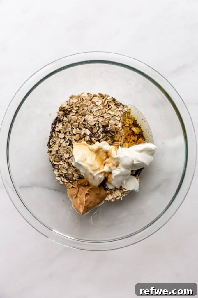 Dreamy Cookie Dough Oats 5 Wet ingredients: oats, chia seeds, yogurt, maple syrup, vanilla extract, almond extract, and cashew butter in a mixing bowl.
