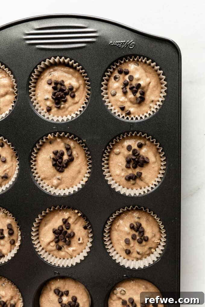 Wholesome Banana Oat Muffins 12 Unbaked oat flour banana muffin batter in a lined baking pan, ready for the oven.