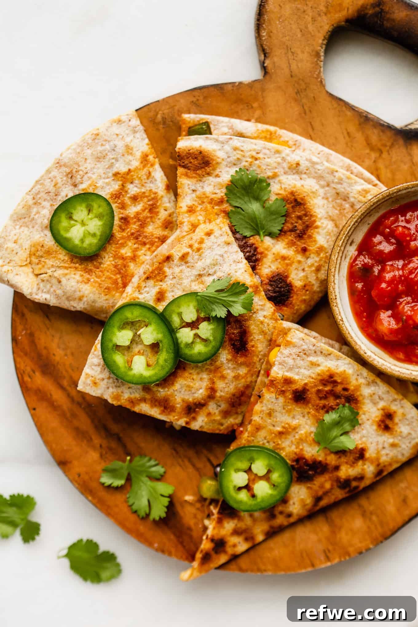 Fiesta Black Bean and Corn Quesadillas 2 Delicious black bean and corn quesadillas cut into triangles on a wooden board, garnished with cilantro.