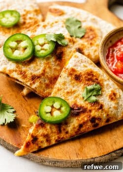 Two quesadillas garnished with sliced jalapeño and cilantro.