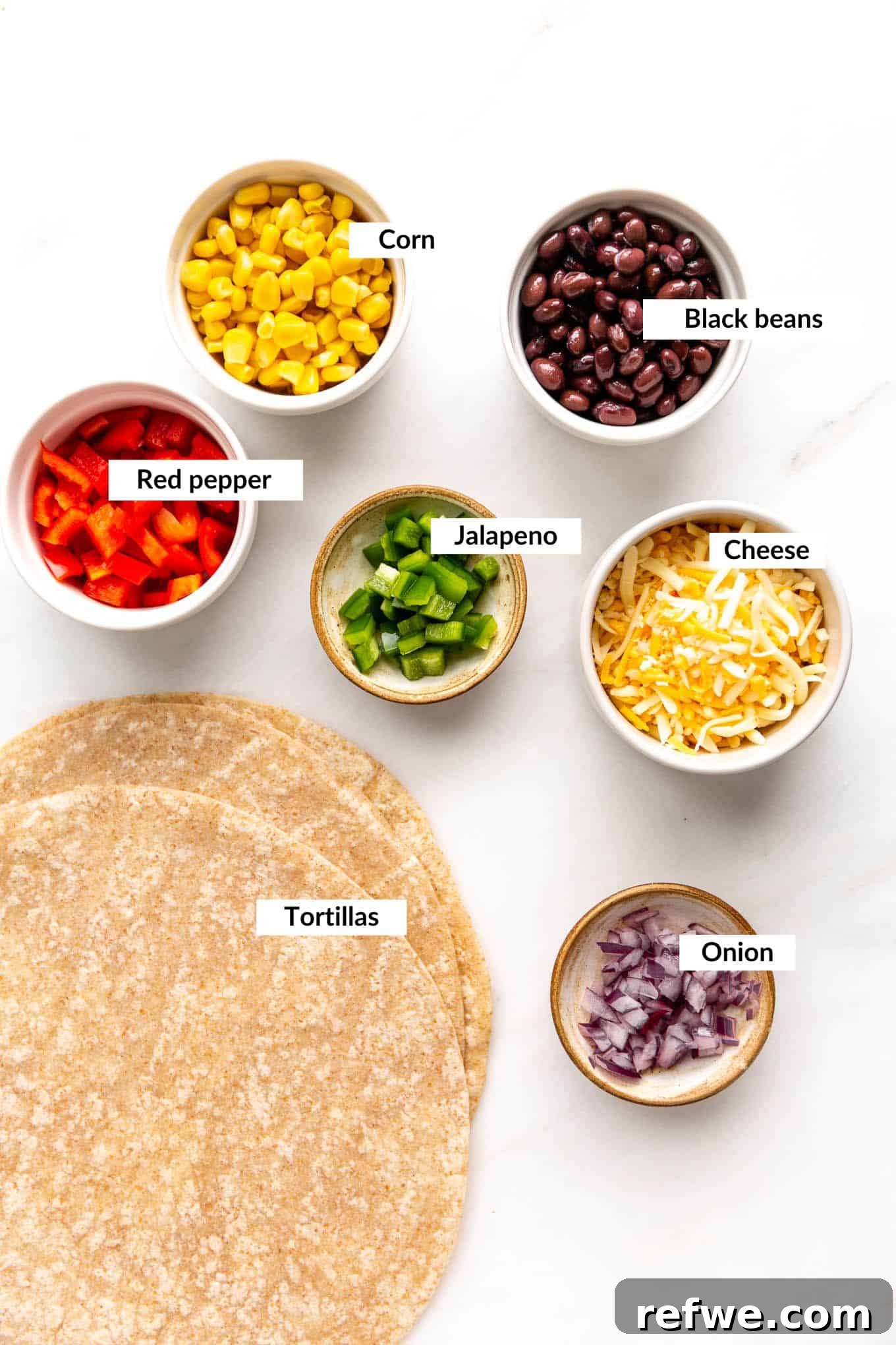 Fiesta Black Bean and Corn Quesadillas 3 A flat lay of fresh ingredients for black bean and corn quesadillas including tortillas, cheese, corn, black beans, onions, and jalapeño.
