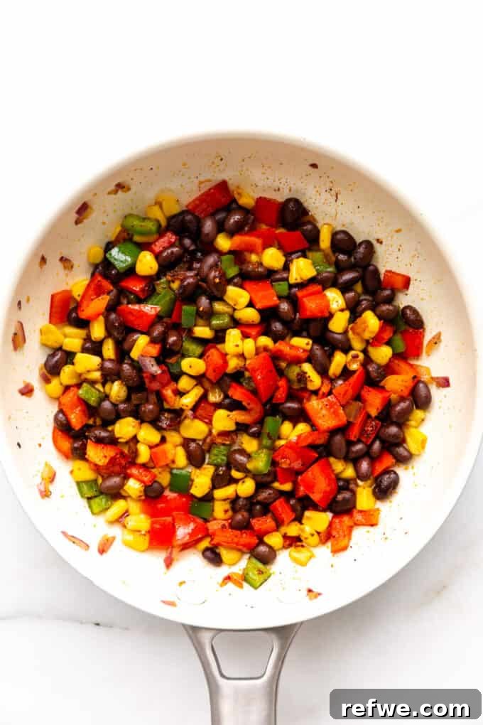 Fiesta Black Bean and Corn Quesadillas 5 A mix of cooked vegetables, black beans, and corn with spices in a pan.