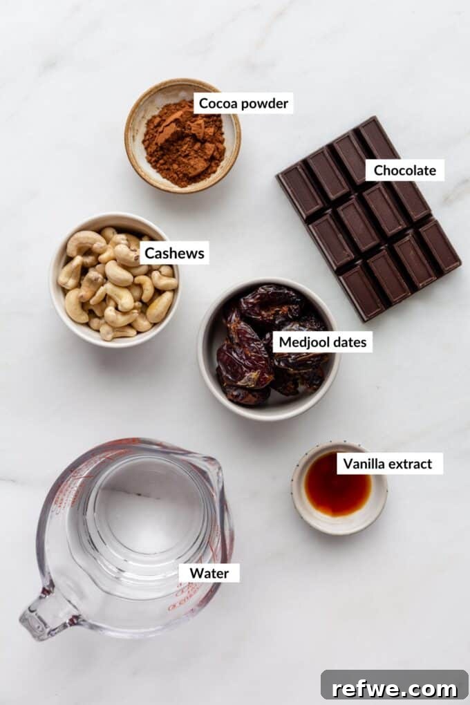 A selection of fresh, high-quality ingredients for making vegan chocolate pudding, including raw cashews, Medjool dates, cocoa powder, vanilla extract, and dark chocolate.