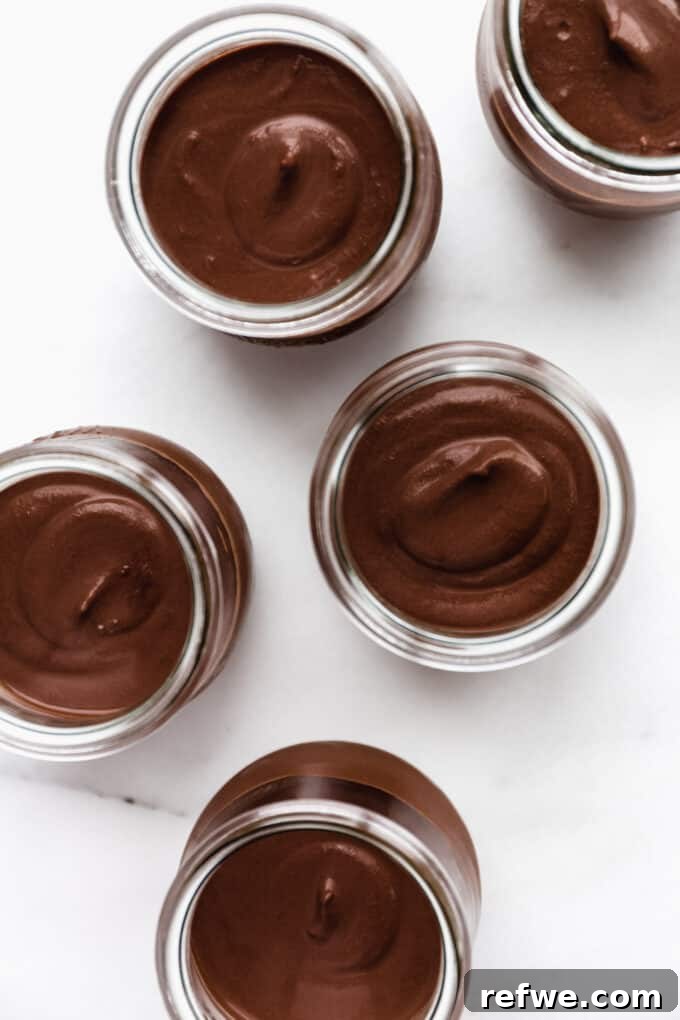 Four charming cups filled with freshly blended vegan chocolate pudding, awaiting their chilling time to set perfectly.