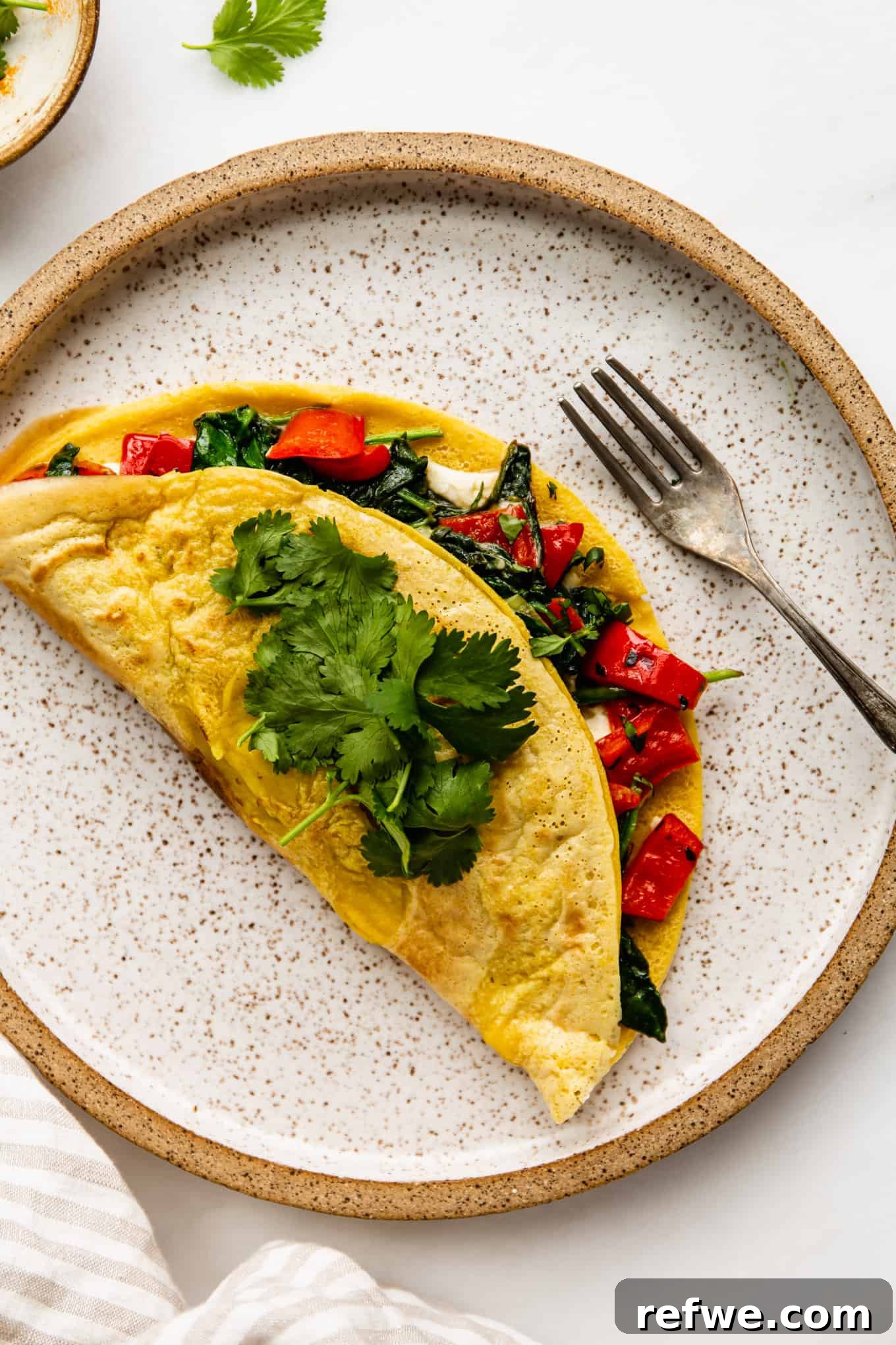 a chickpea flour omlette stuffed with peppers and spinach on a ceramic plate