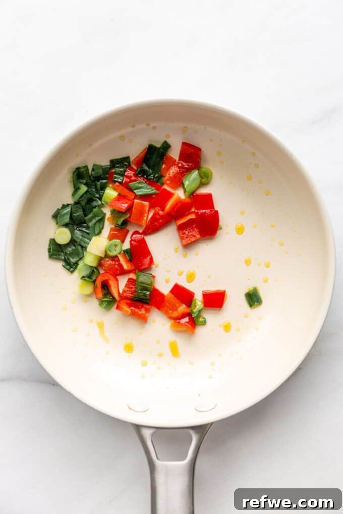 green onions and red peppers in a pan