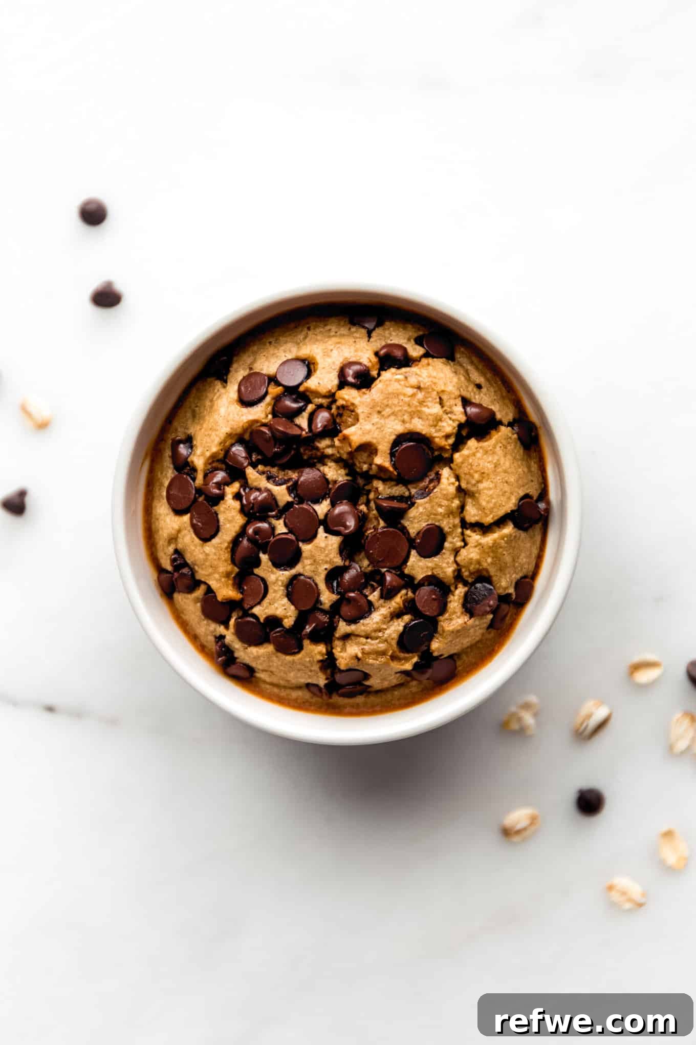 Cookie Dough Baked Oatmeal 8 A freshly baked ramekin of cookie baked oatmeal with a few chocolate chips visible on the side, cooling slightly