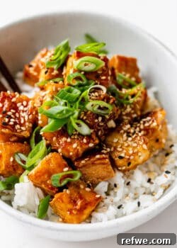 Crispy honey garlic tofu topped with fresh scallions and sesame seeds, presented in a bowl.