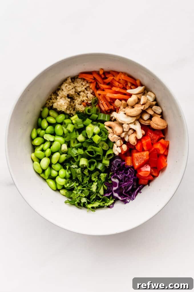 Wholesome Quinoa Edamame Crunch Bowl 4 Edamame beans, quinoa, cashews, and various vegetables in a salad bowl, before dressing