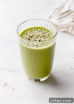 A glass of green protein smoothie with a beige napkin on the side