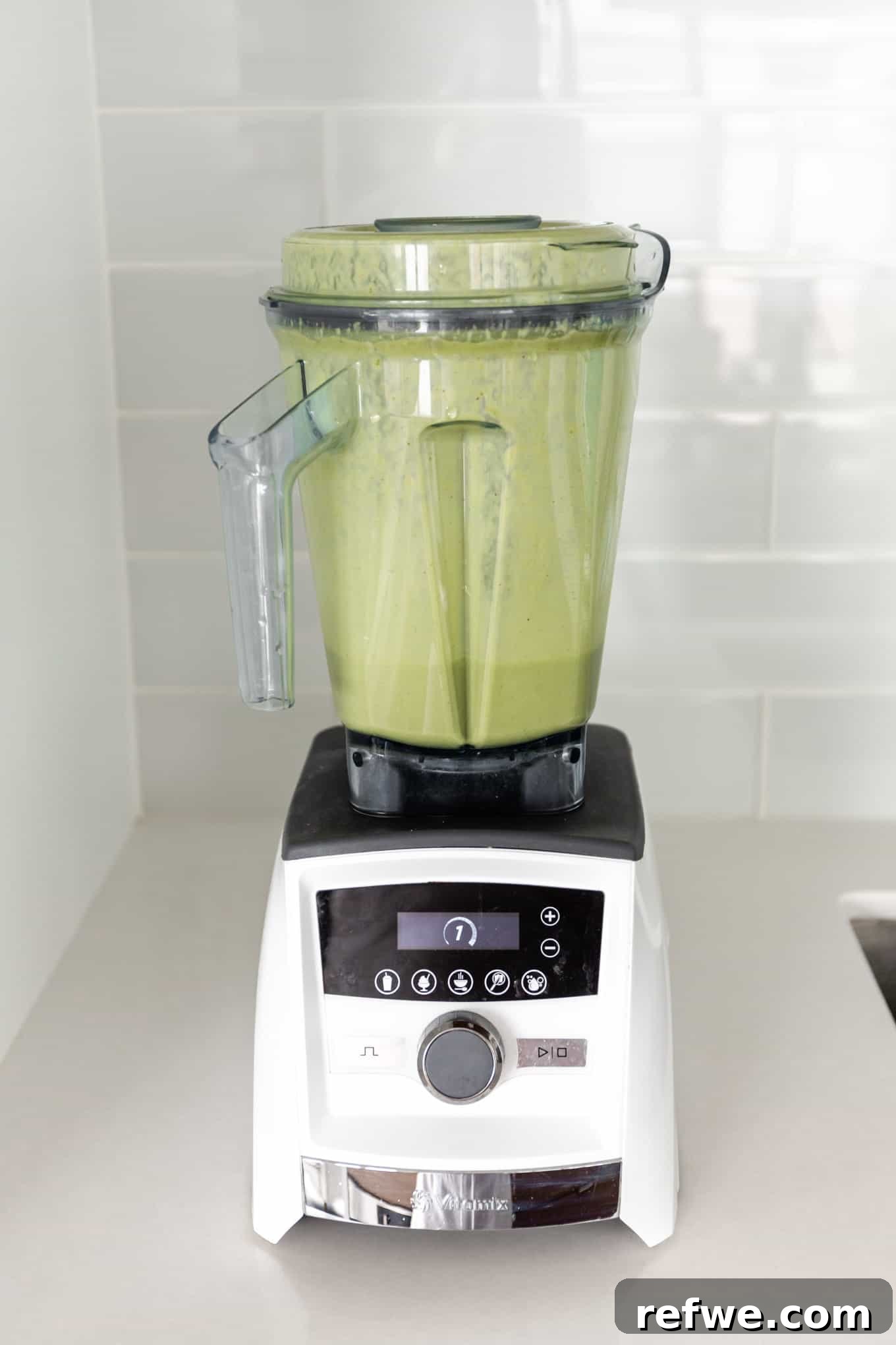 Supercharged Green Protein Smoothie 5 The green protein smoothie blends smoothly in a blender, forming a vibrant, creamy mixture, ready to be poured.